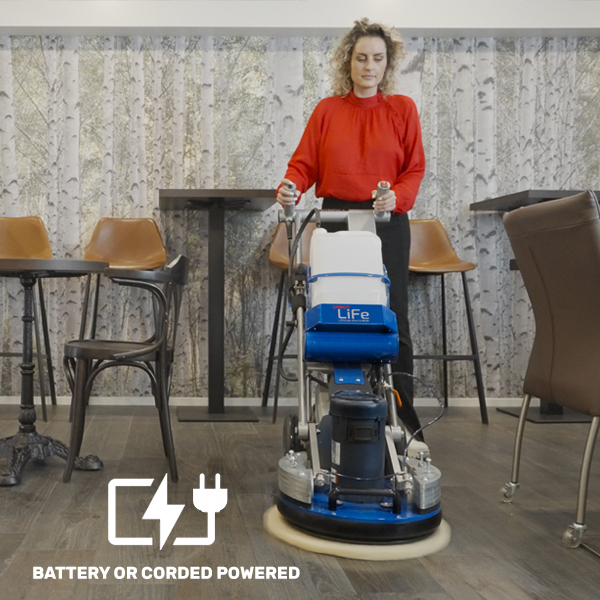 a woman in a red shirt is using a floor scruber.